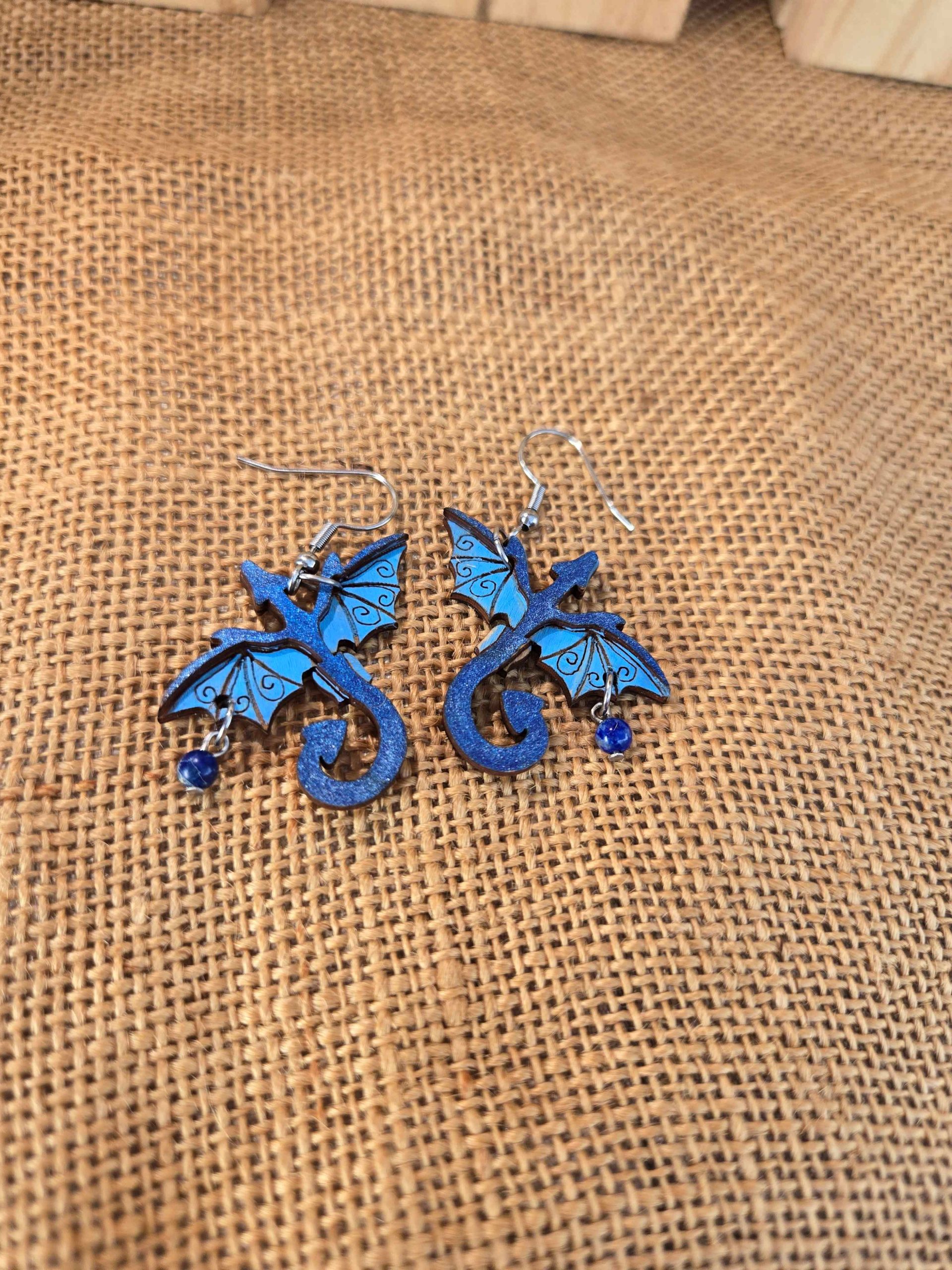 Layered wooden dragon dangle earrings with stainless steel hooks and small crystal drops, shown in natural finishes and available in multiple colours.