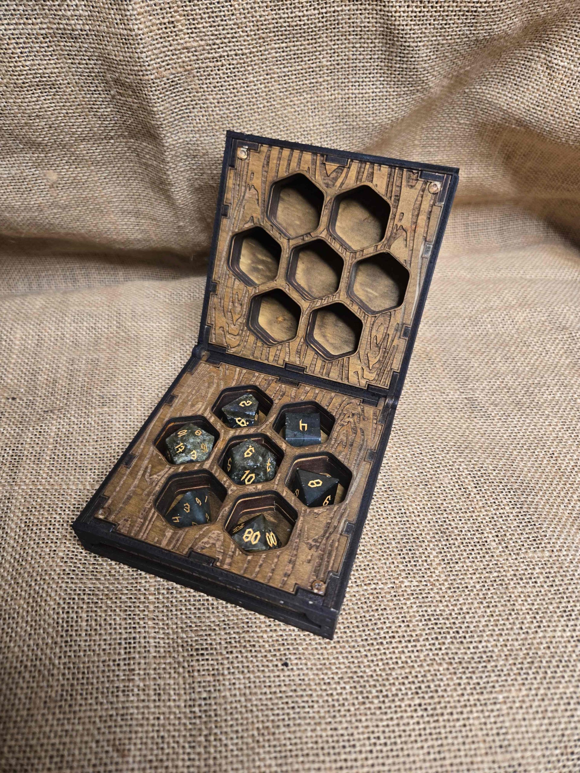 Open wooden dice box displaying a full set of labradorite polyhedral dice inside fitted compartments.