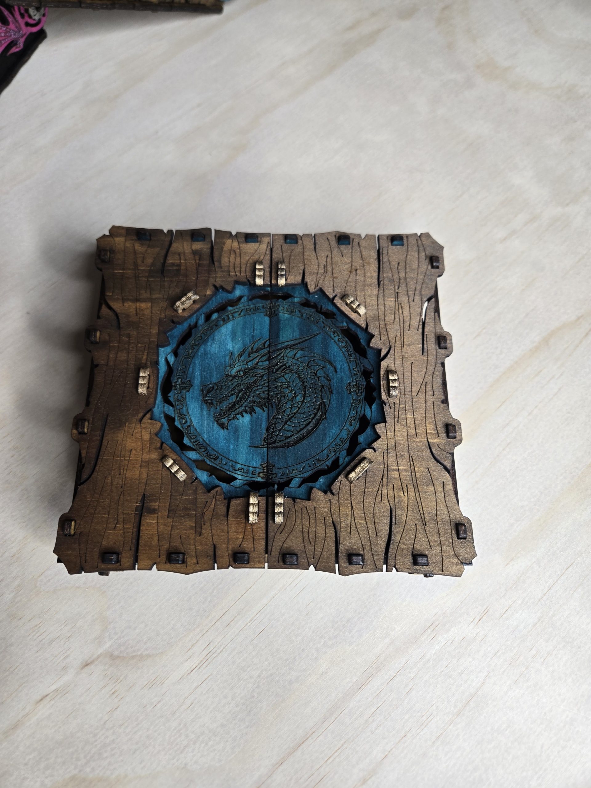 Closed handcrafted wooden two-door dragon box with engraved dragon and wing details, finished in natural woodgrain.