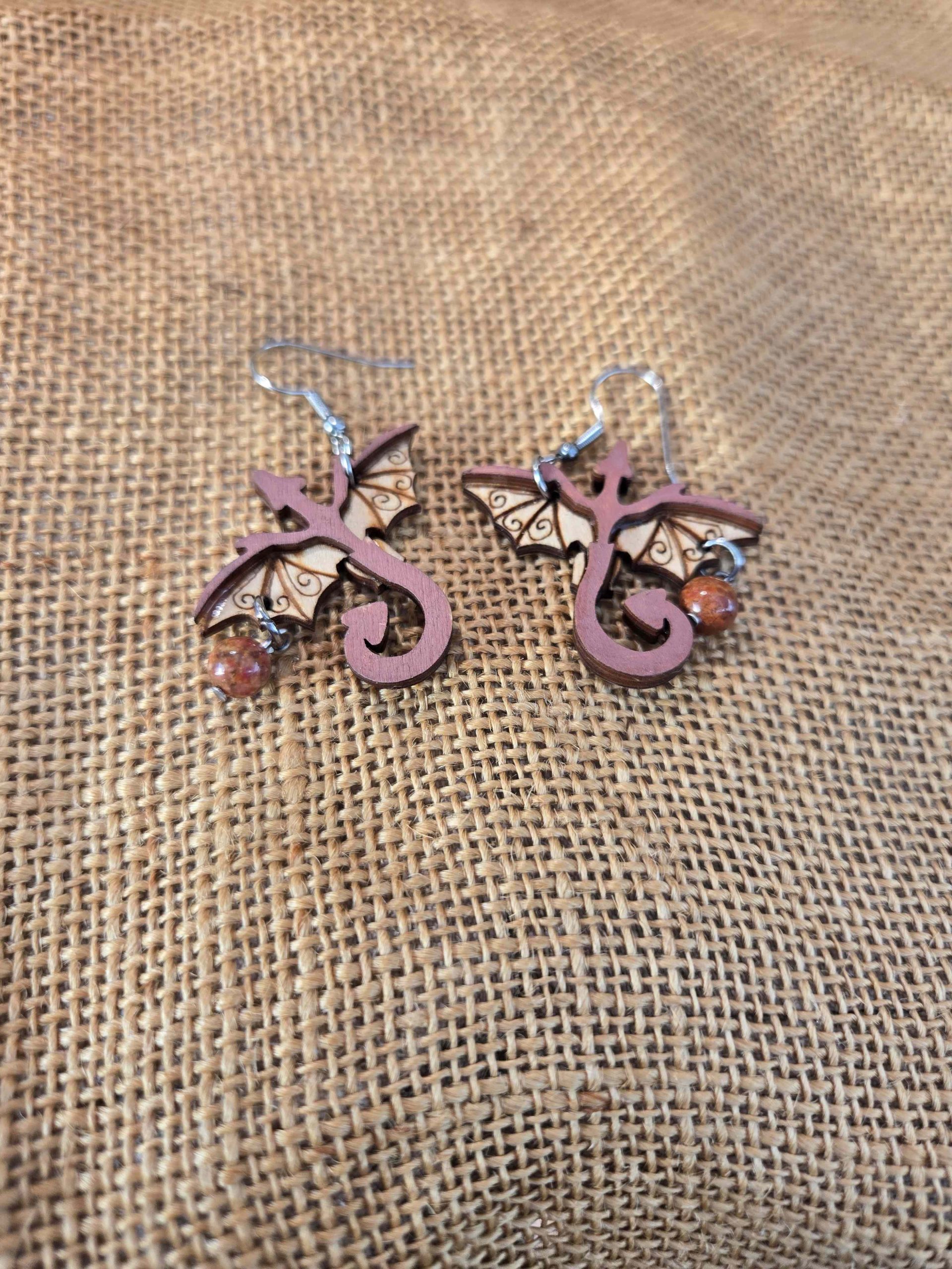 Layered wooden dragon dangle earrings with stainless steel hooks and small crystal drops, shown in natural finishes and available in multiple colours.