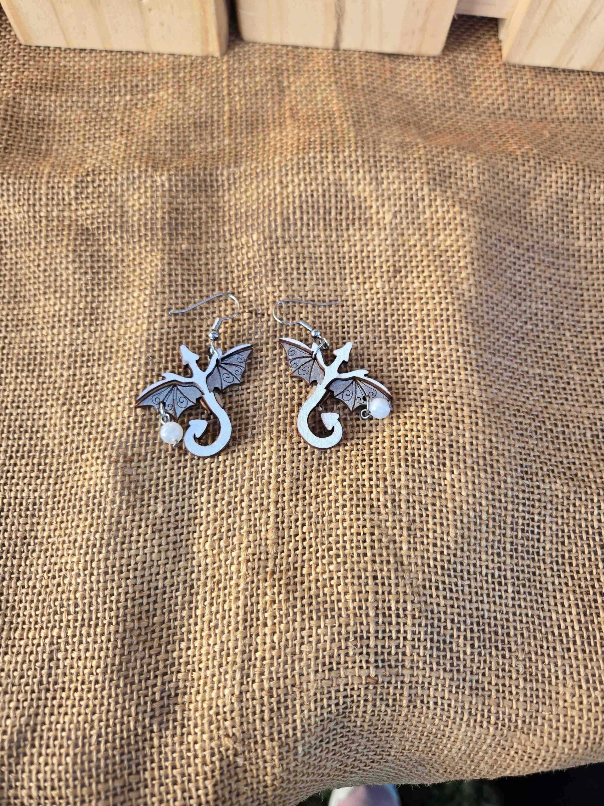 Layered wooden dragon dangle earrings with stainless steel hooks and small crystal drops, shown in natural finishes and available in multiple colours.