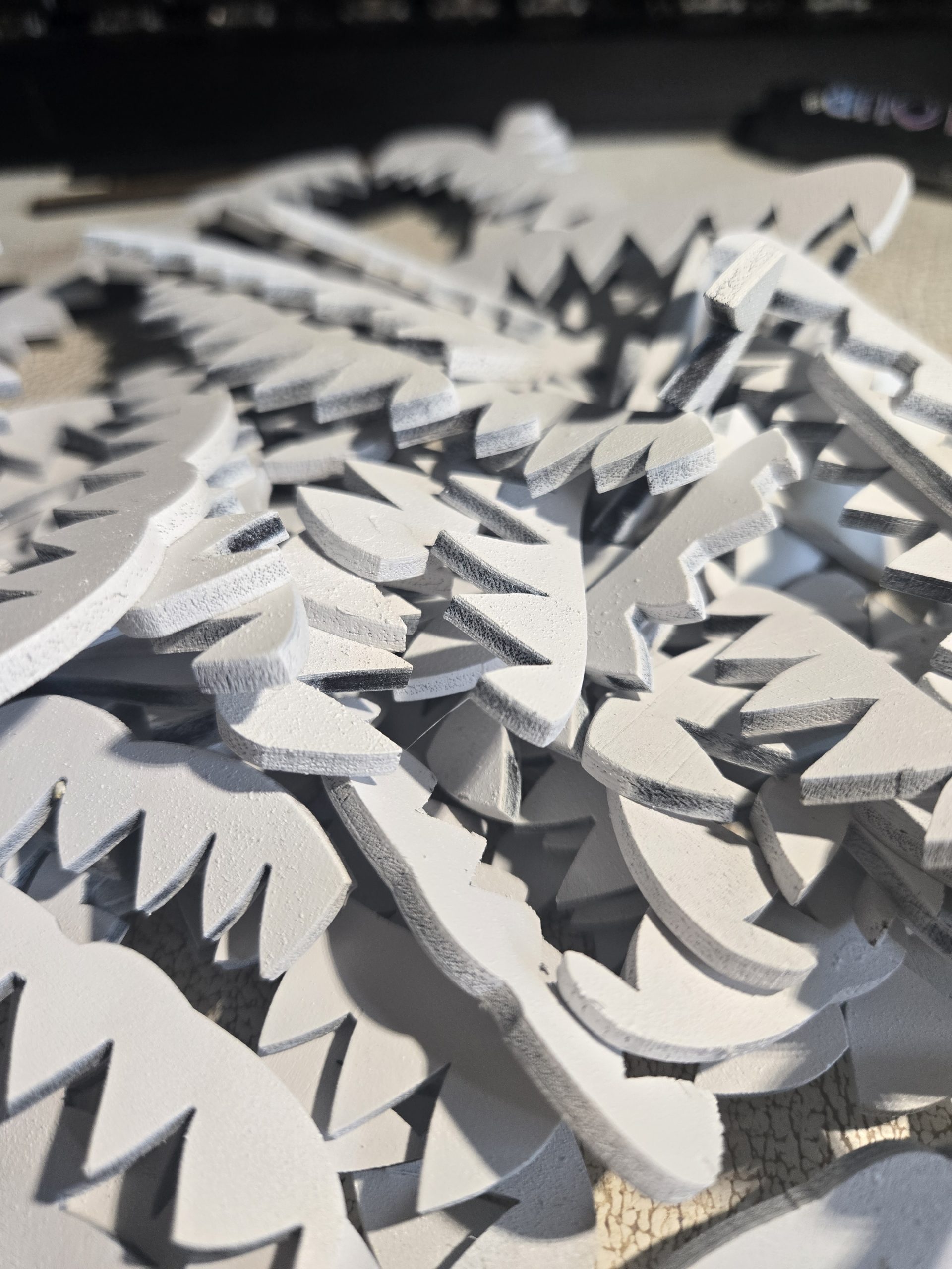 Laser-cut wooden mimic teeth laid out during the production process for handcrafted fantasy mimic chests.