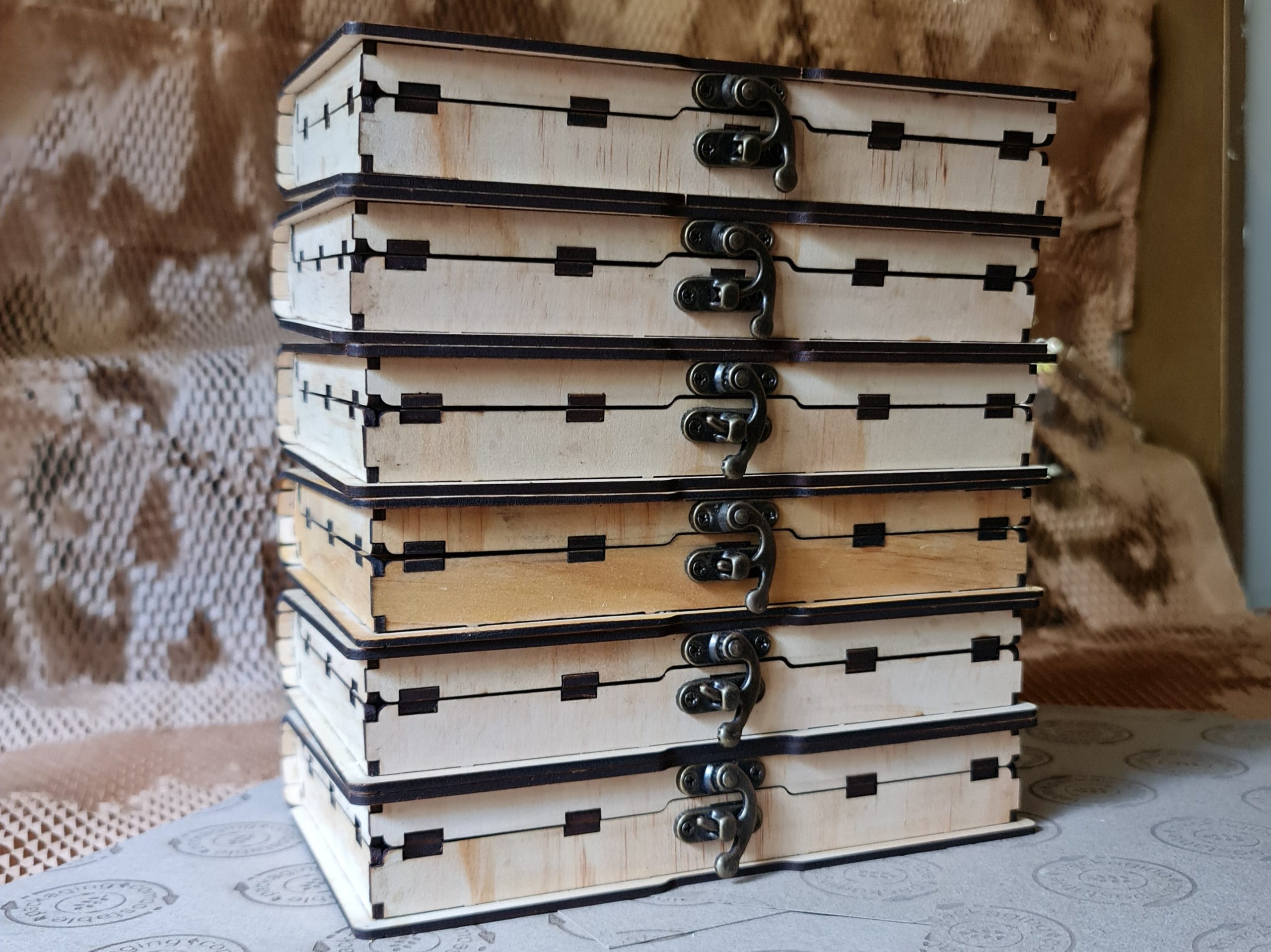 Stacked wooden book boxes displayed to highlight metal latch details and layered book-style construction.