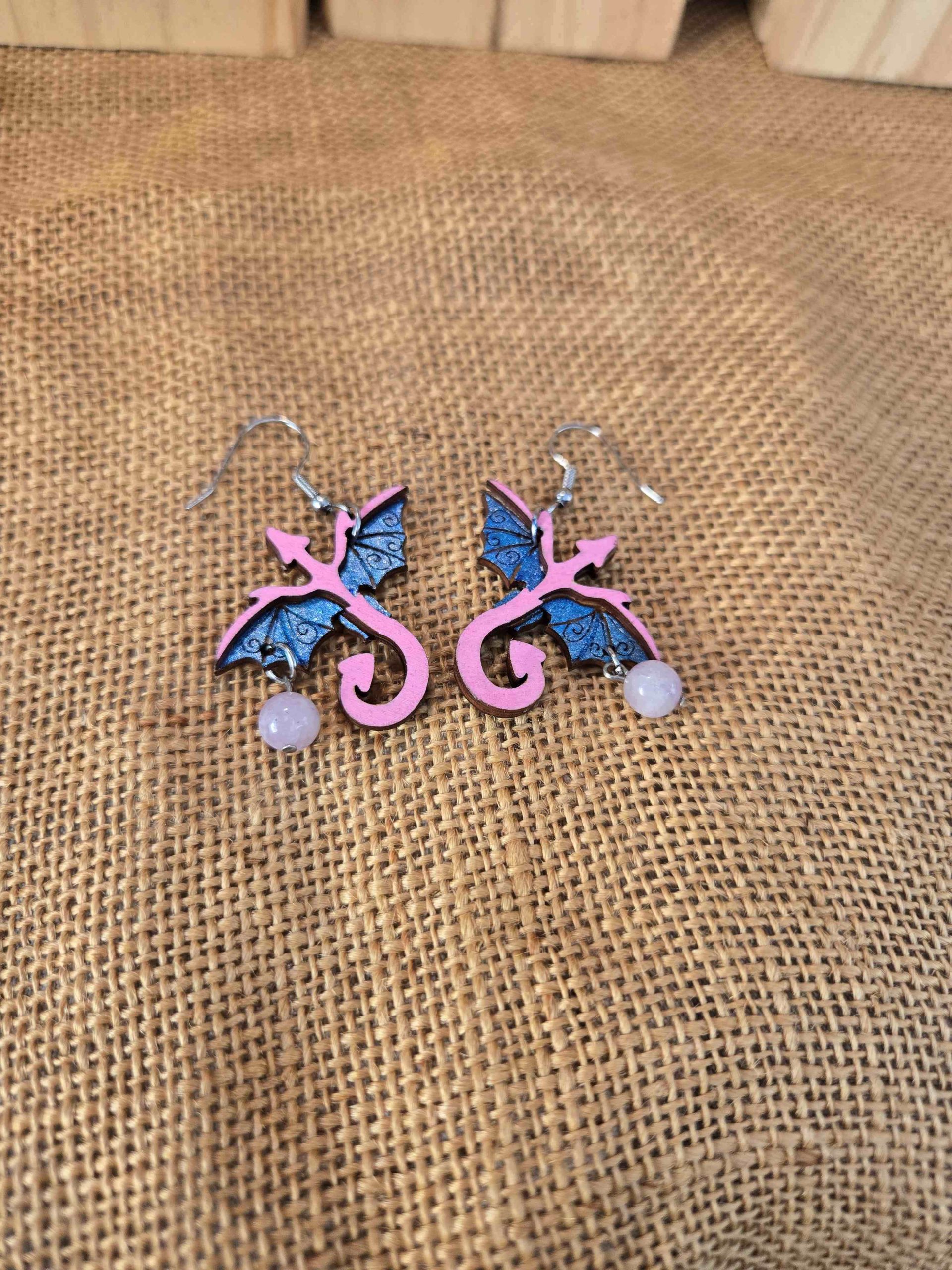 Layered wooden dragon dangle earrings with stainless steel hooks and small crystal drops, shown in natural finishes and available in multiple colours.