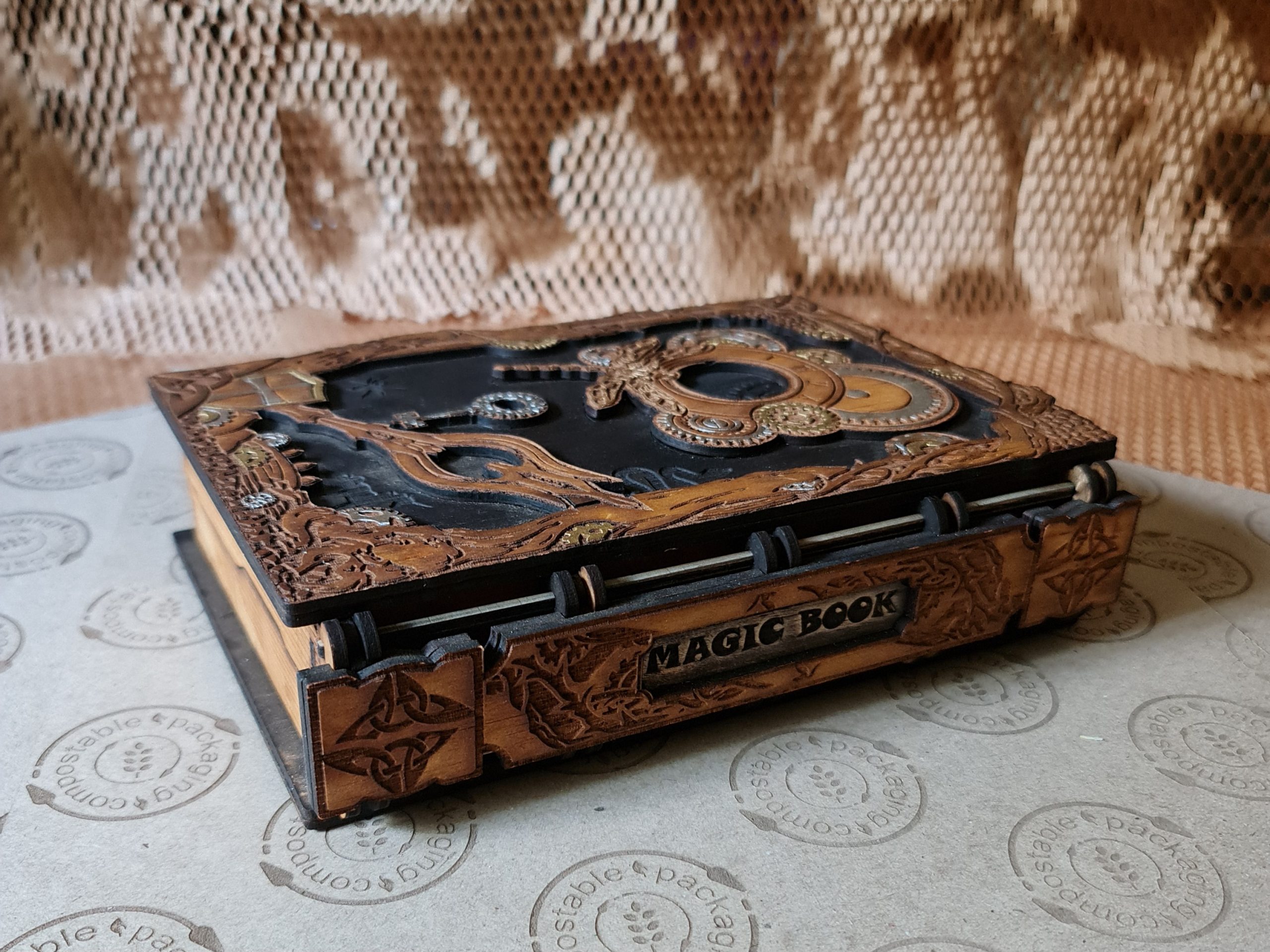 Steampunk-inspired wooden book box with engraved gears and “magic book” spine, opening to reveal storage or a dice tray.