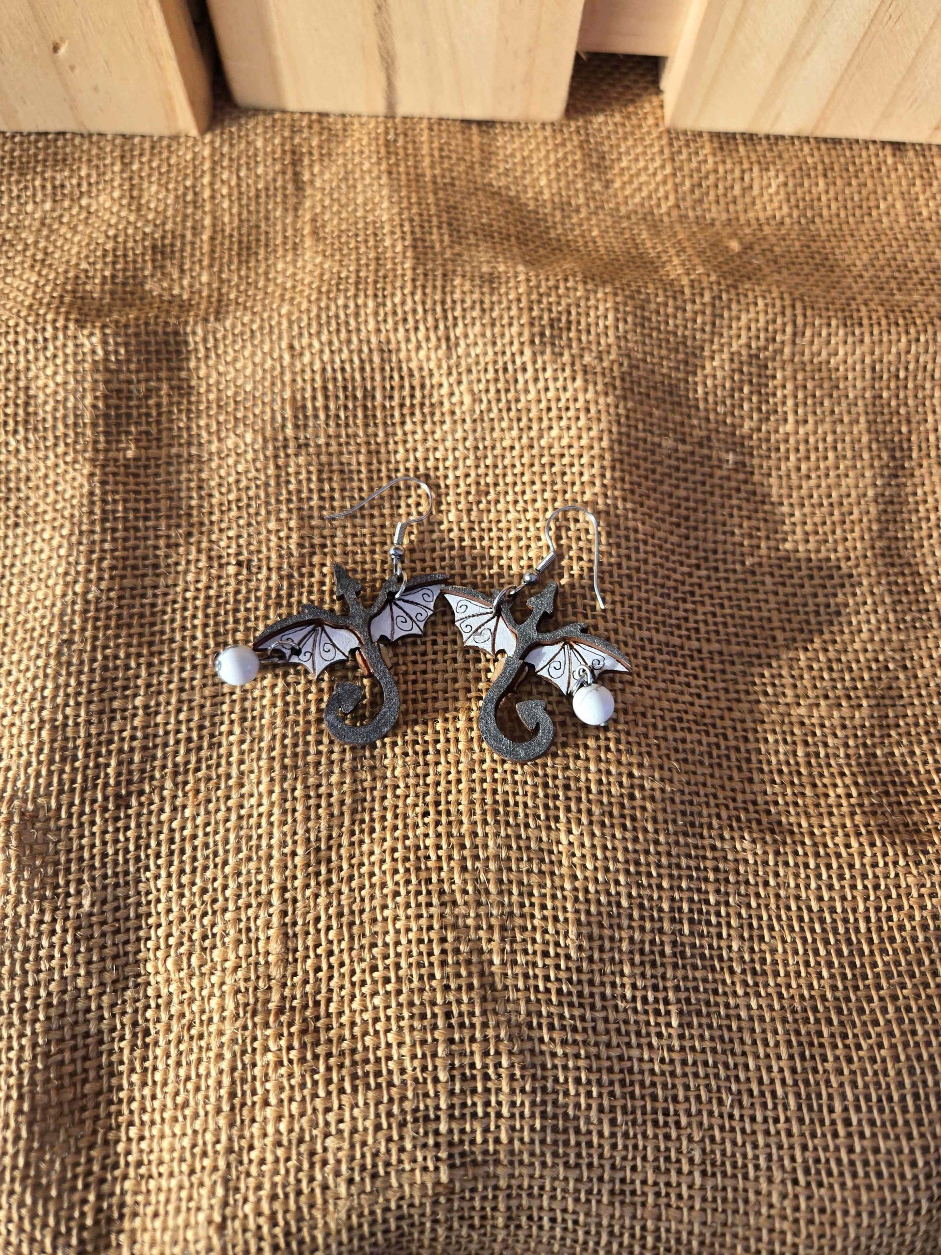 Layered wooden dragon dangle earrings with stainless steel hooks and small crystal drops, shown in natural finishes and available in multiple colours.
