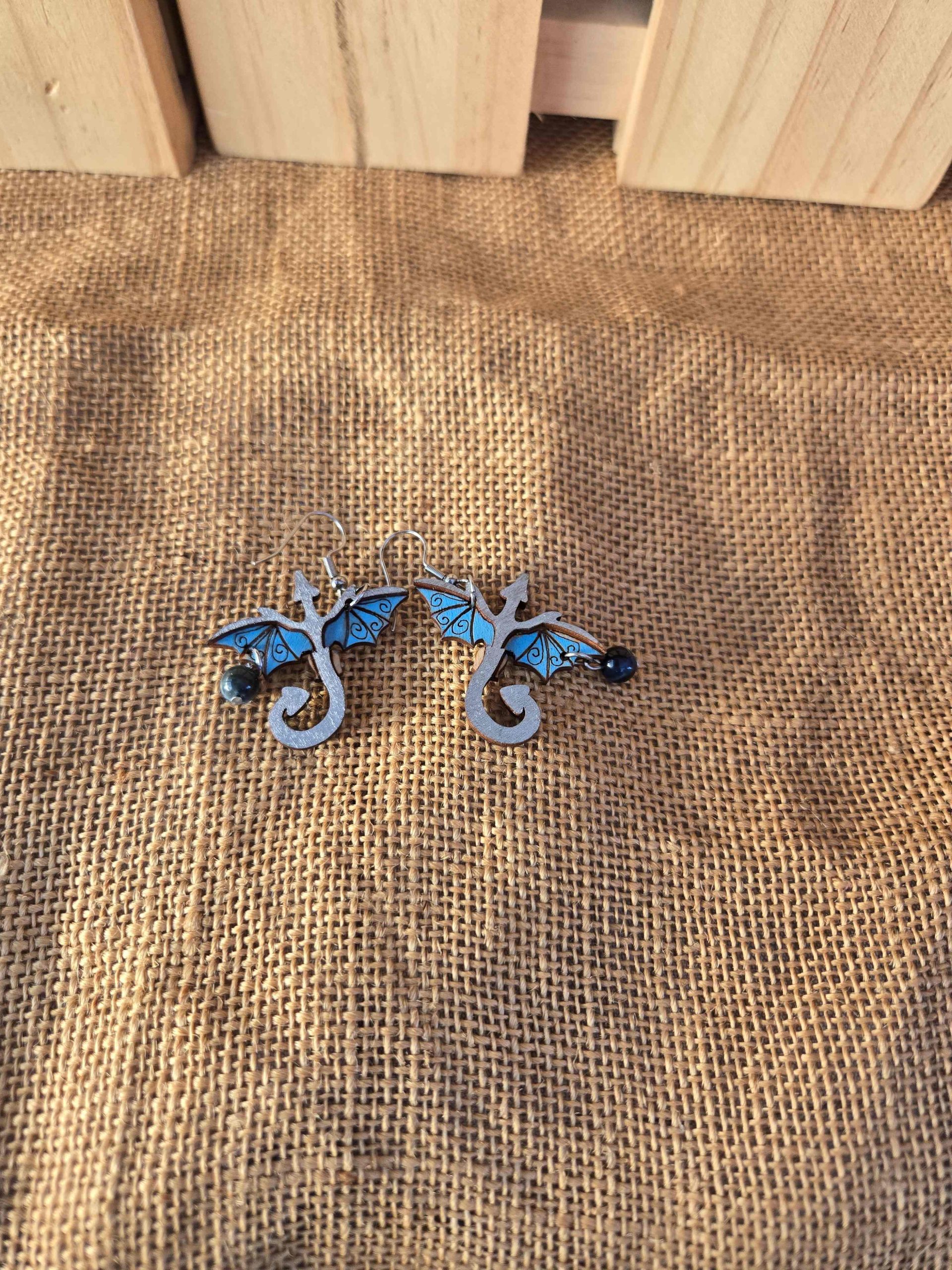 Layered wooden dragon dangle earrings with stainless steel hooks and small crystal drops, shown in natural finishes and available in multiple colours.