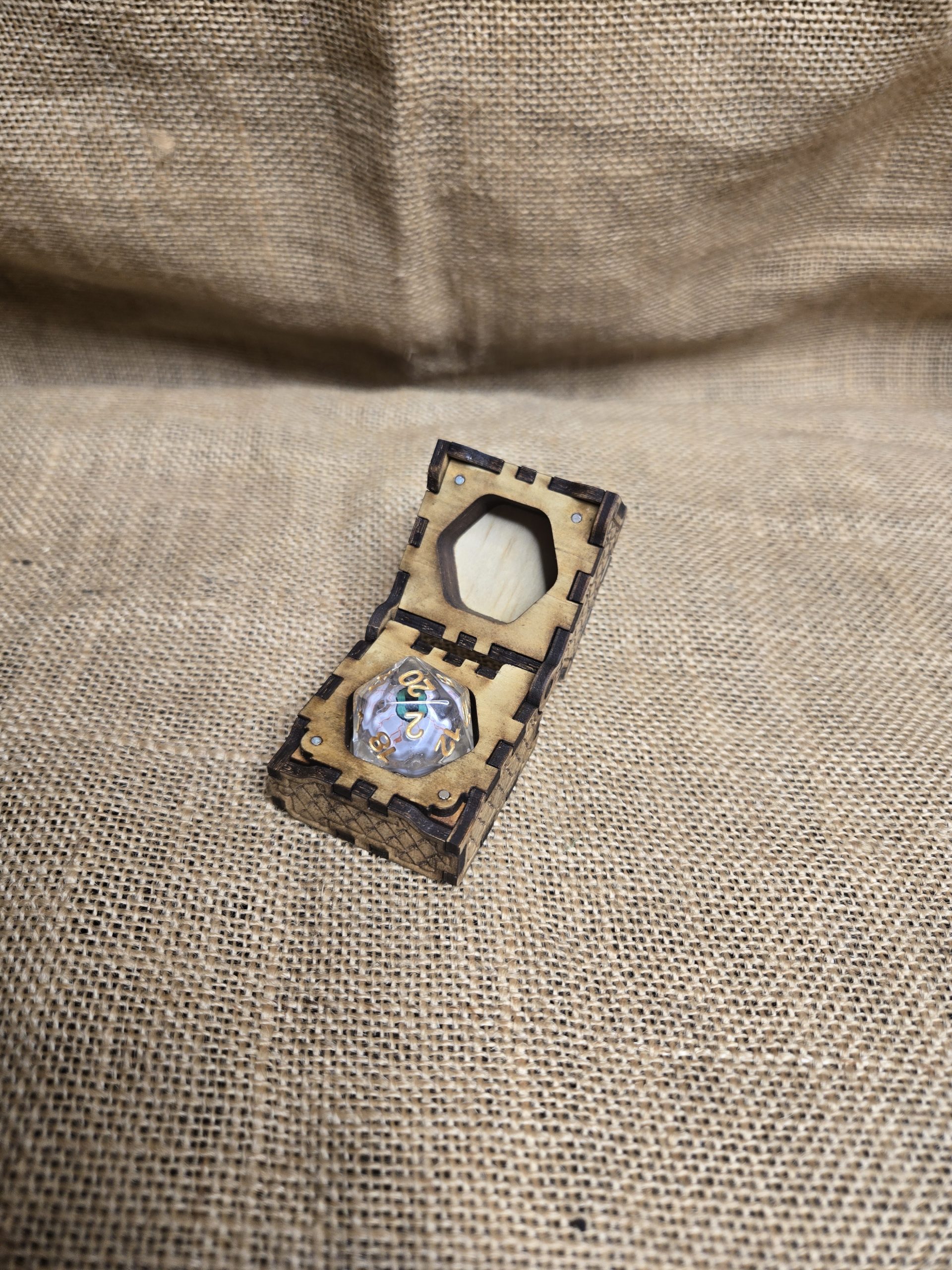 Open wooden single dice box showing an eyeball-style fantasy die inside, finished in natural timber.