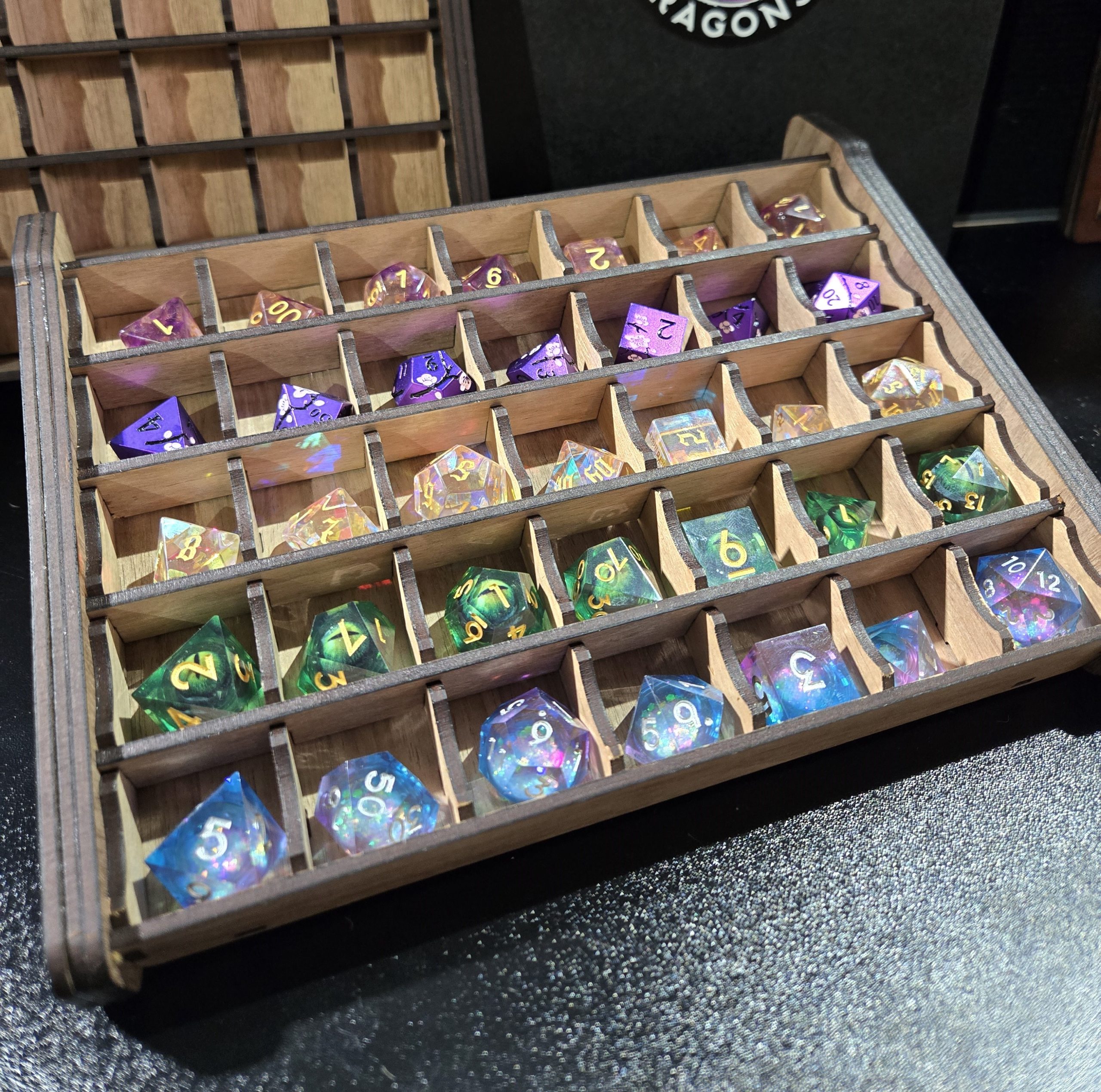 Handcrafted wooden dice gear for tabletop RPGs, including dice boxes, dice towers, dice jails and dice trays, shown with colourful dice.